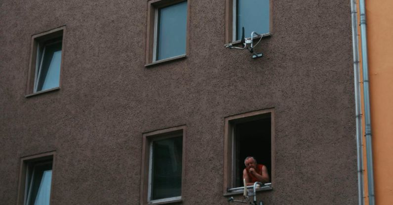 Infrastructure Cost - Person in simple apartment building window